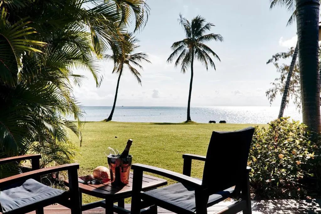 Terrasse mit Blick auf Palmen und das Meer im Hintergrund