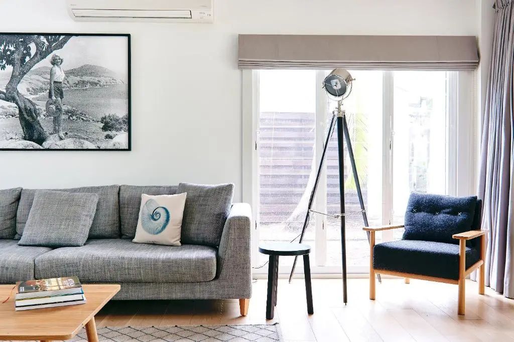 Stylisches Wohnzimmer mit grauem Sofa, großer Lampe und Kunst an der Wand