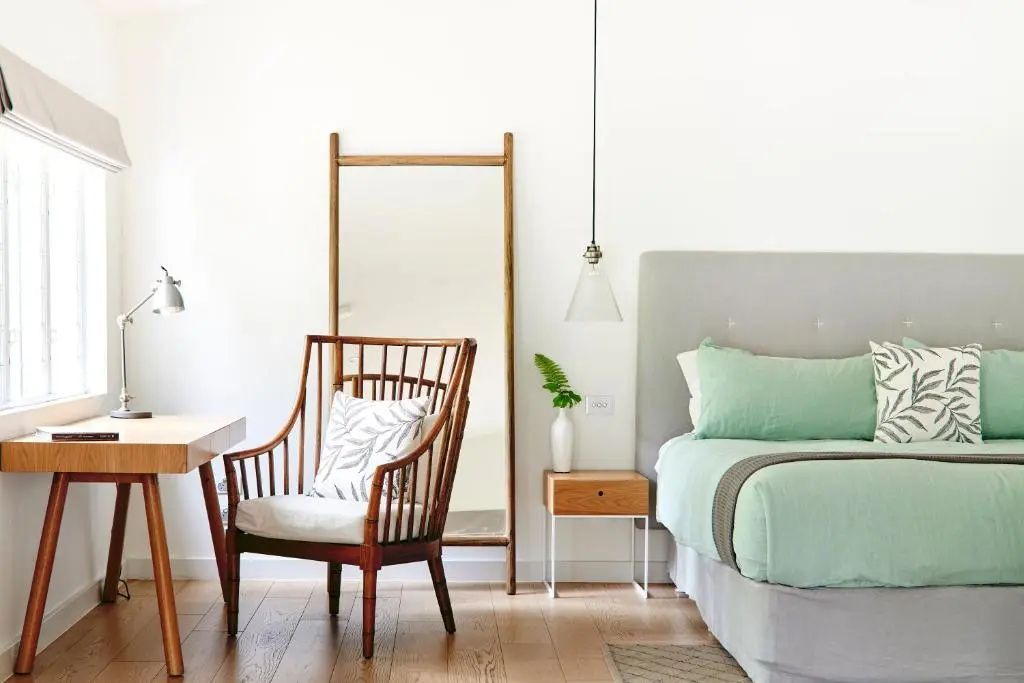 Schlafbereich mit pastellfarbenem Bett, stylischer Stuhl und dezentem Dekor