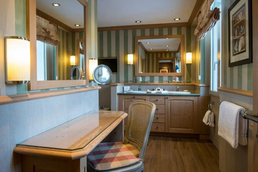 Elegantes Badezimmer in einer klassischen Junior-Suite mit Holzmöbeln und Spiegeln.