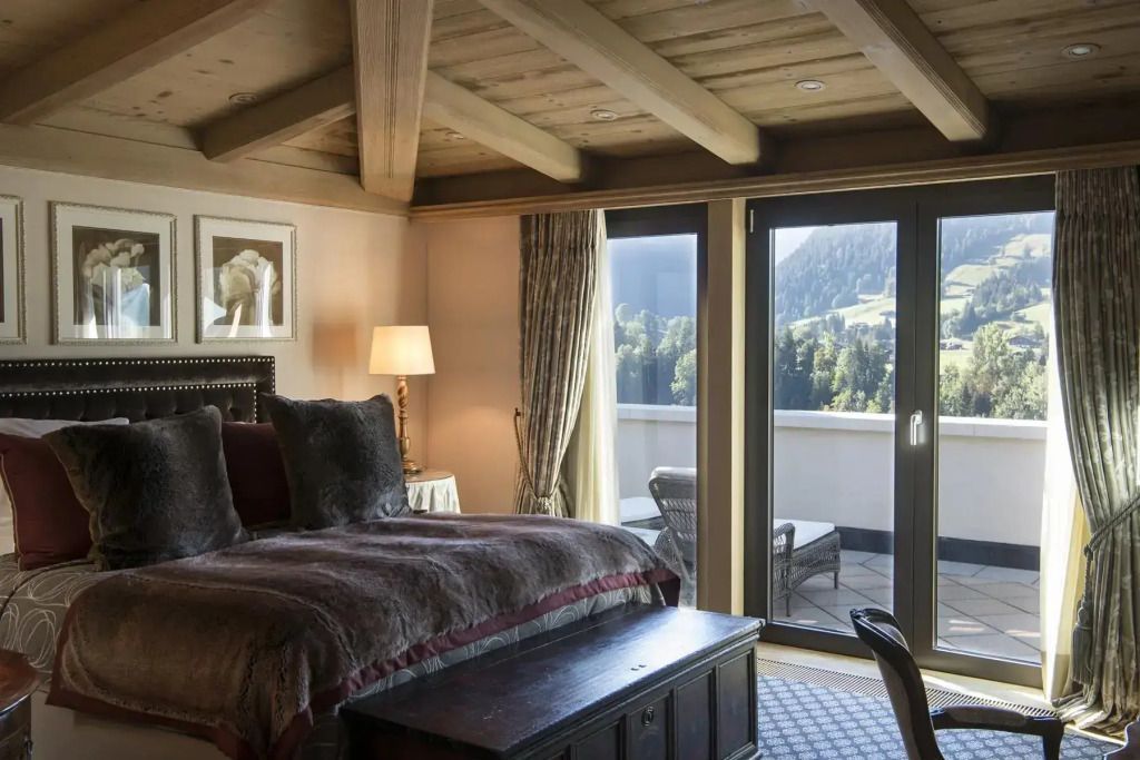 Gemütliches Schlafzimmer mit Holzbalkendecke und Terrasse mit Bergblick.