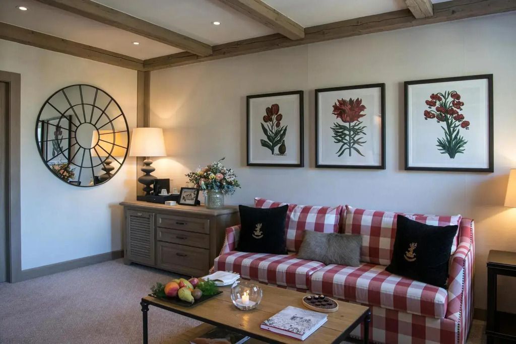 Gemütlicher Wohnbereich mit rotem kariertem Sofa und botanischer Kunst.