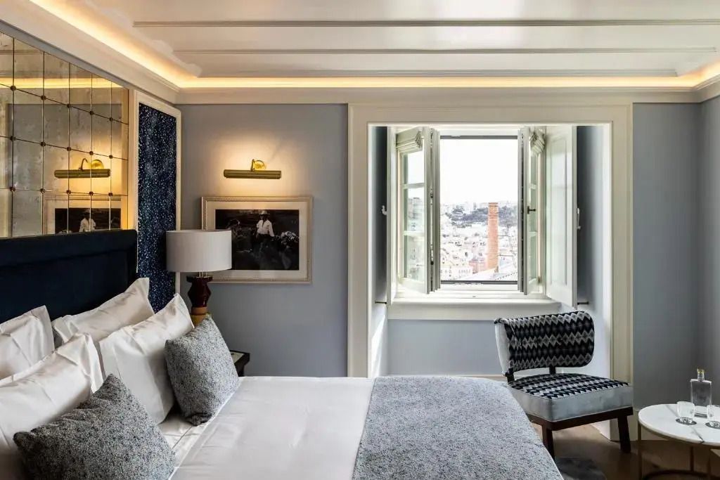 Elegantes Hotelzimmer mit Doppelbett, offenes Fenster mit Aussicht, stilvolle Beleuchtung
