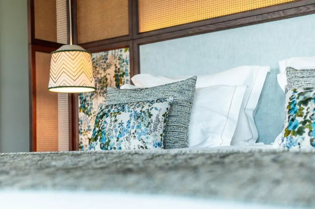 Nahaufnahme eines Hotelbettes mit dekorativen Kissen und Lampen