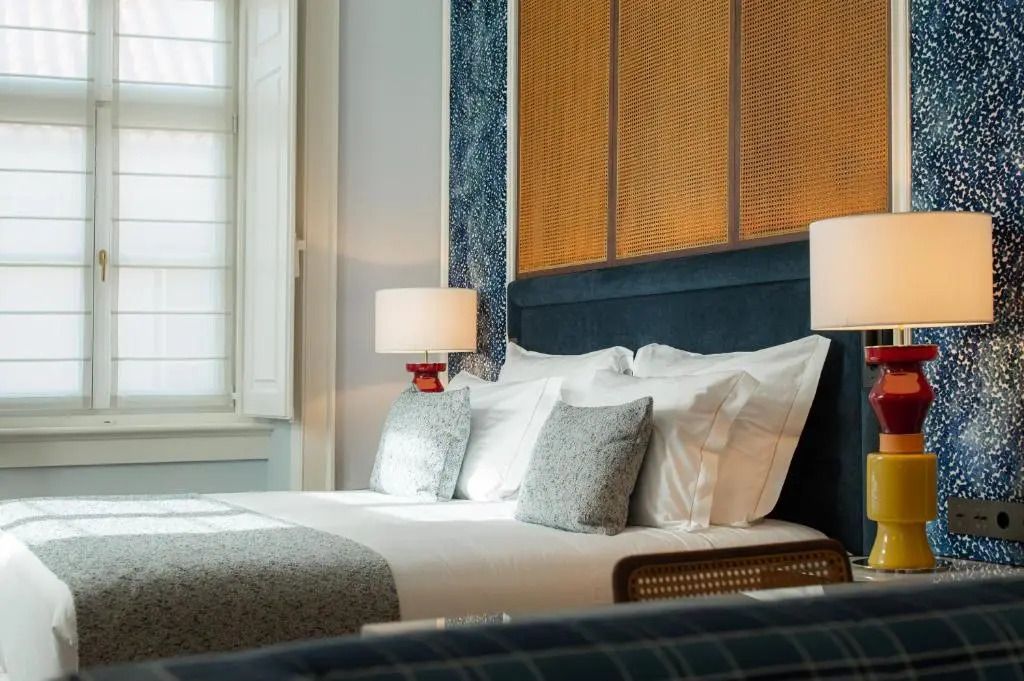 Nahaufnahme eines eleganten Betts in einer Junior-Suite mit Lampen und Polstermöbeln.