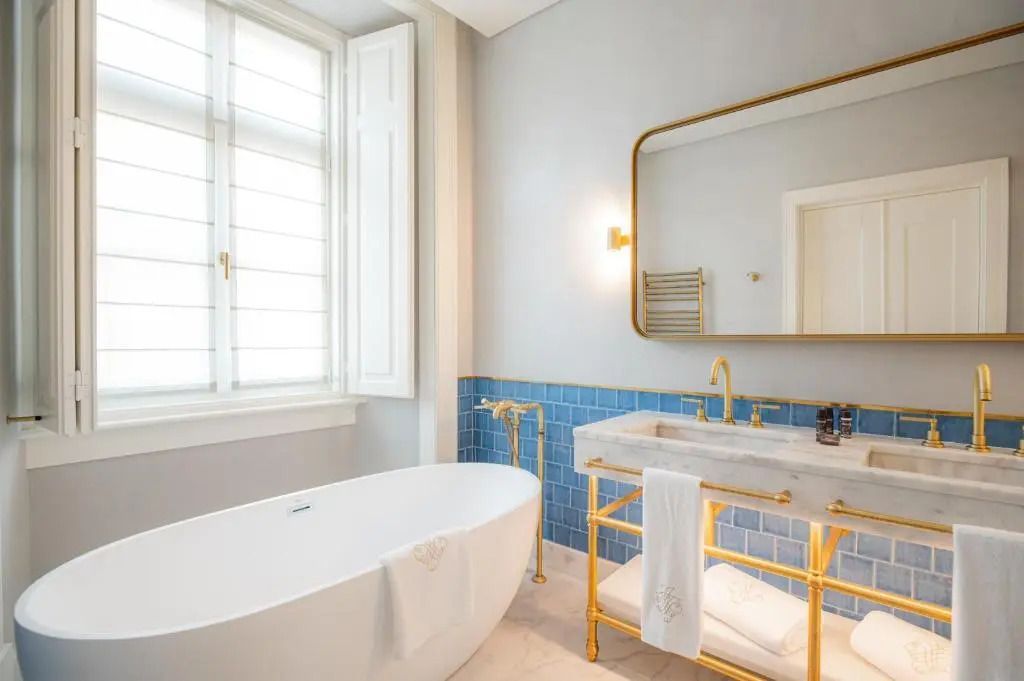 Luxuriöses Badezimmer mit freistehender Badewanne und goldenen Akzenten.