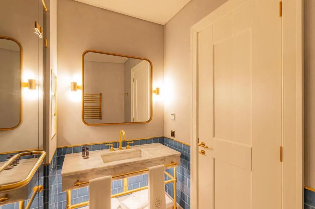 Modernes Badezimmer mit goldenen Armaturen und großem Spiegel