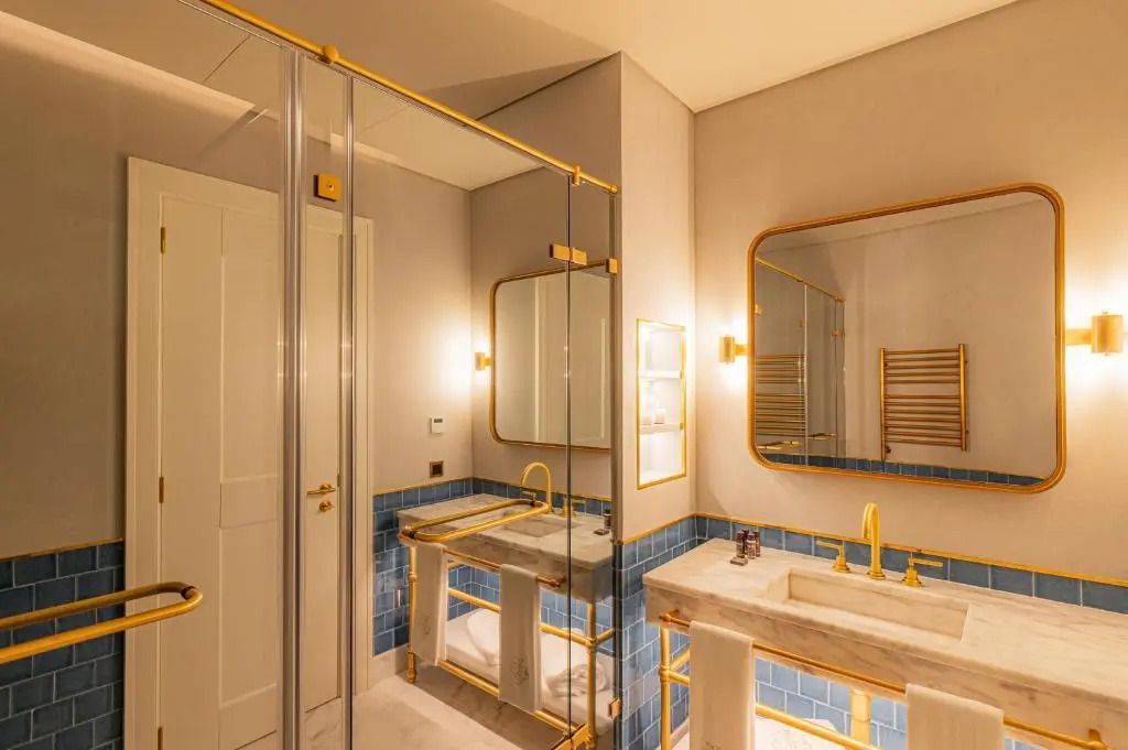 Badezimmer mit großer Spiegelfläche und hochwertiger Ausstattung in Goldtönen.
