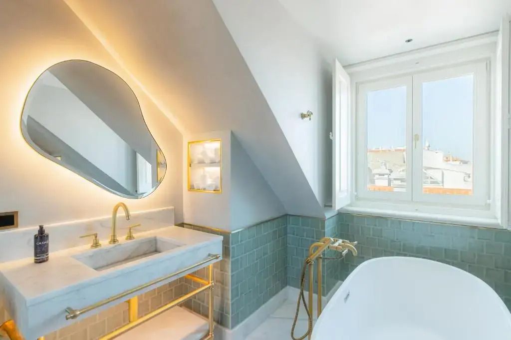 Moderner Waschtisch im Badezimmer mit rundem Spiegel und goldenen Armaturen