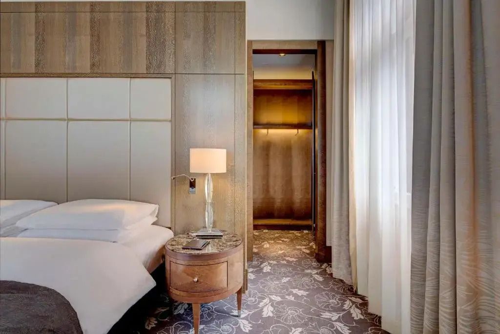 Elegantes Schlafzimmer mit Bett und Holzdetails in einer Suite des Anantara Palais Hansen Hotels