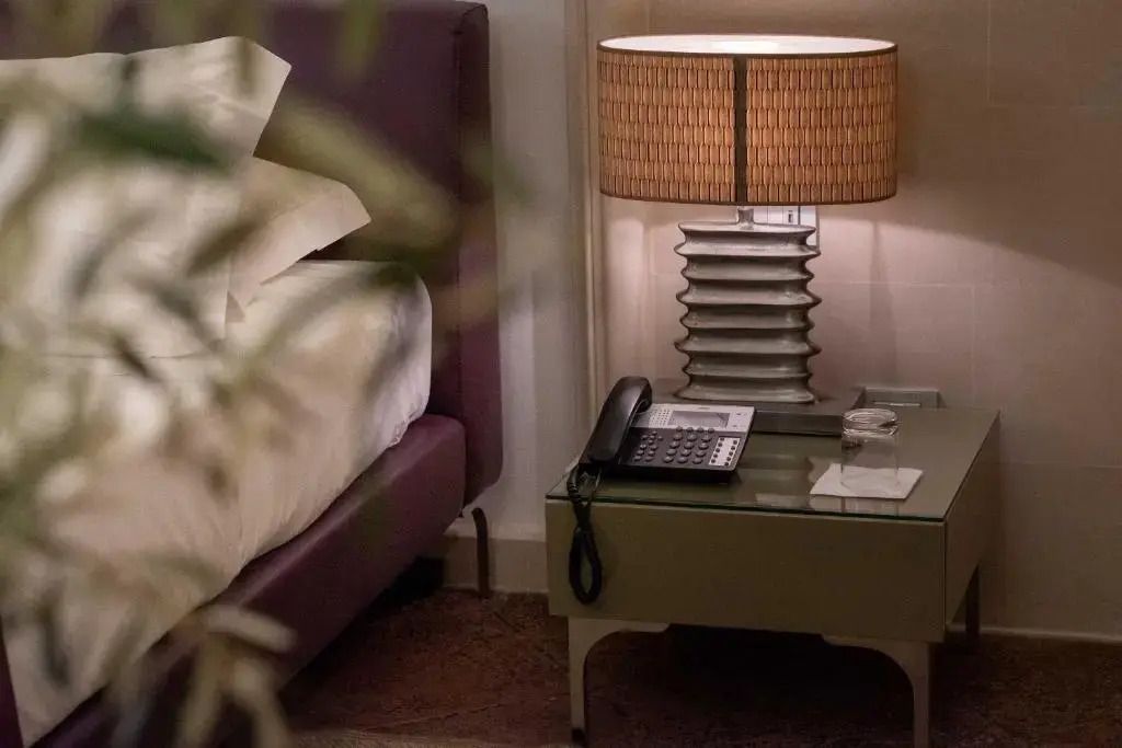 Nachttisch mit luxuriösem Tischtelefon und Lampe im Superior Suite Schlafzimmer.