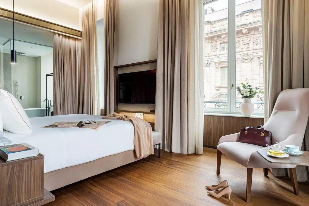 Geräumiges Schlafzimmer mit großen Fenstern und Blick auf historische Gebäude