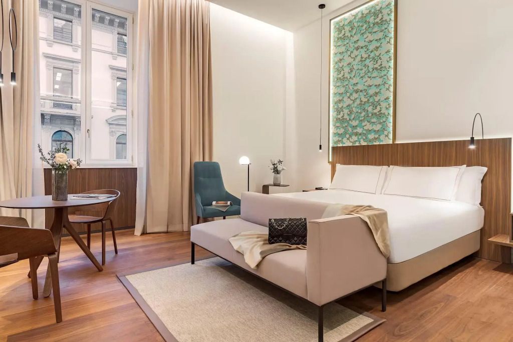 Modernes Hotelzimmer mit Doppelbett, eleganter Sitzgelegenheit und hohem Fenster