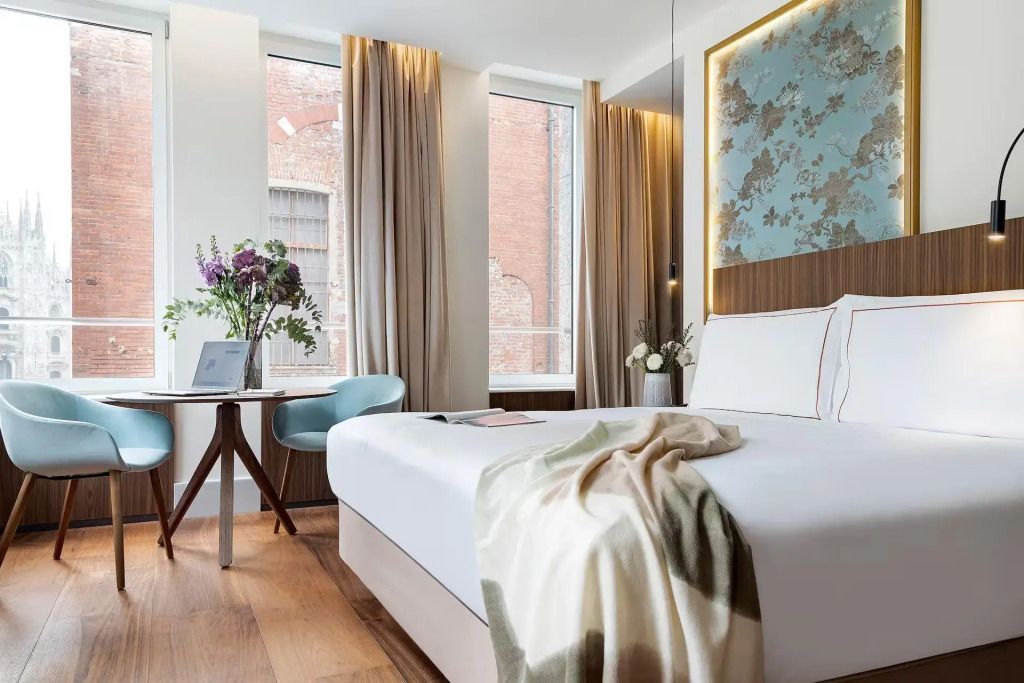 Helles Schlafzimmer in der Duomo Doppel Suite mit großem Fenster und stilvoller Dekoration.