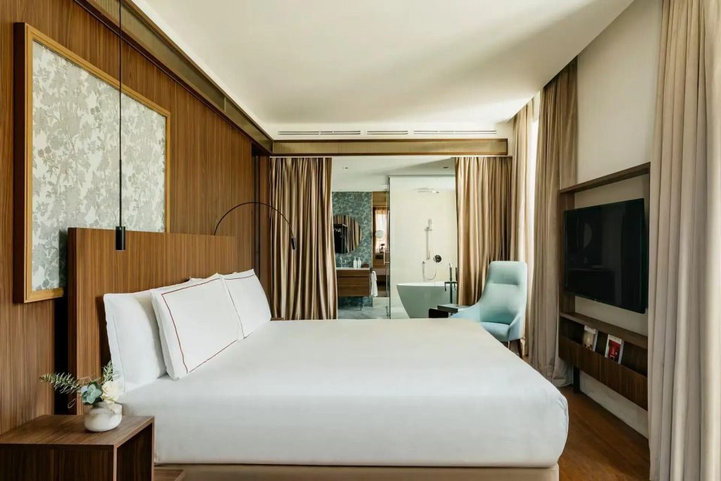 Helles Schlafzimmer mit Doppelbett und freistehender Badewanne im Palazzo Cordusio