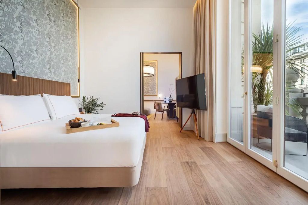 Elegantes Doppelzimmer mit Holzfußboden und Zugang zu einem Balkon