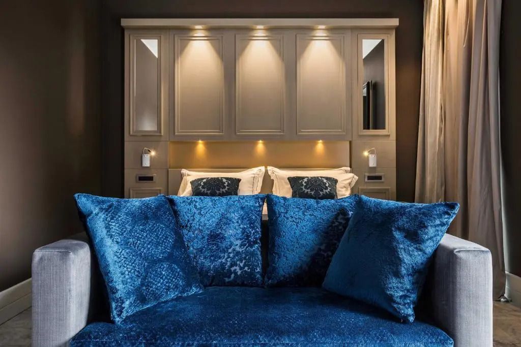 Luxuriöses Doppelbett mit blauen Kissen und stilvoller Beleuchtung