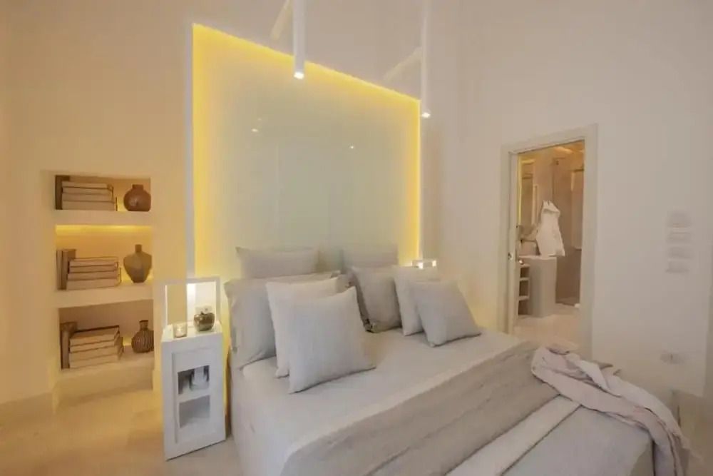 Modernes Bett mit weichen Kissen und beleuchteter Wand im Deluxe Zimmer