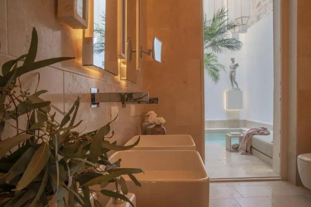 Blick vom Badezimmer zum Innenhof mit Pool und Pflanzen