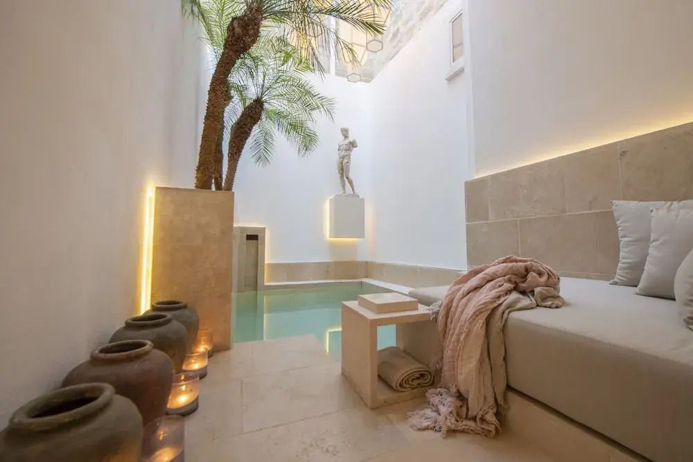 Innenhof mit kleinem Pool und Palme. Statue im Hintergrund
