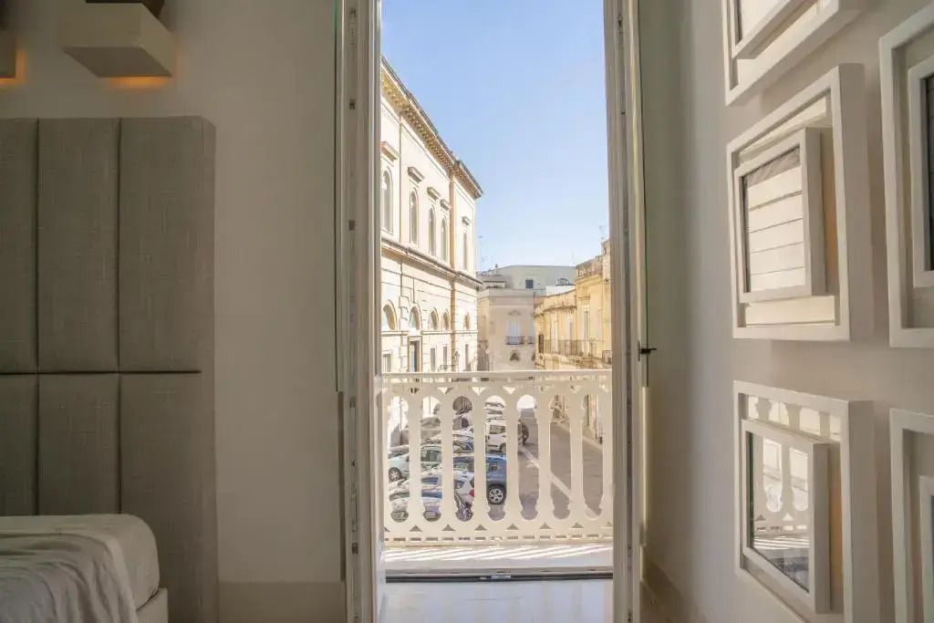 Balkonaussicht von einem Hotelzimmer über historische Gebäude bei klarem Himmel.