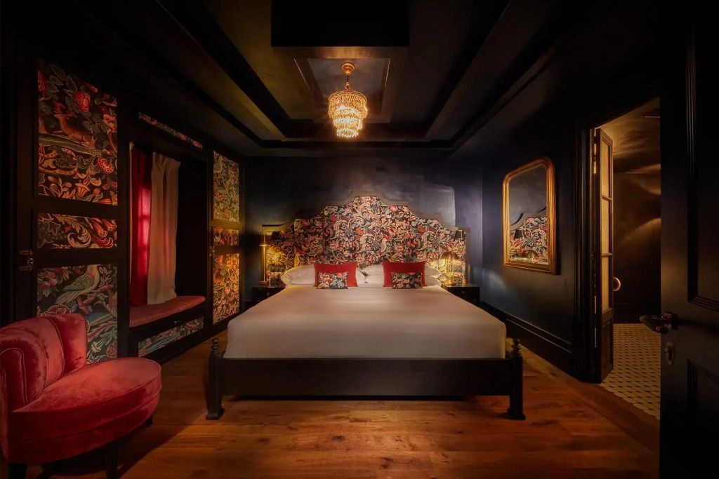 Elegante Suite mit floralem Kopfteil und luxuriösem Bett in stimmungsvoller Beleuchtung