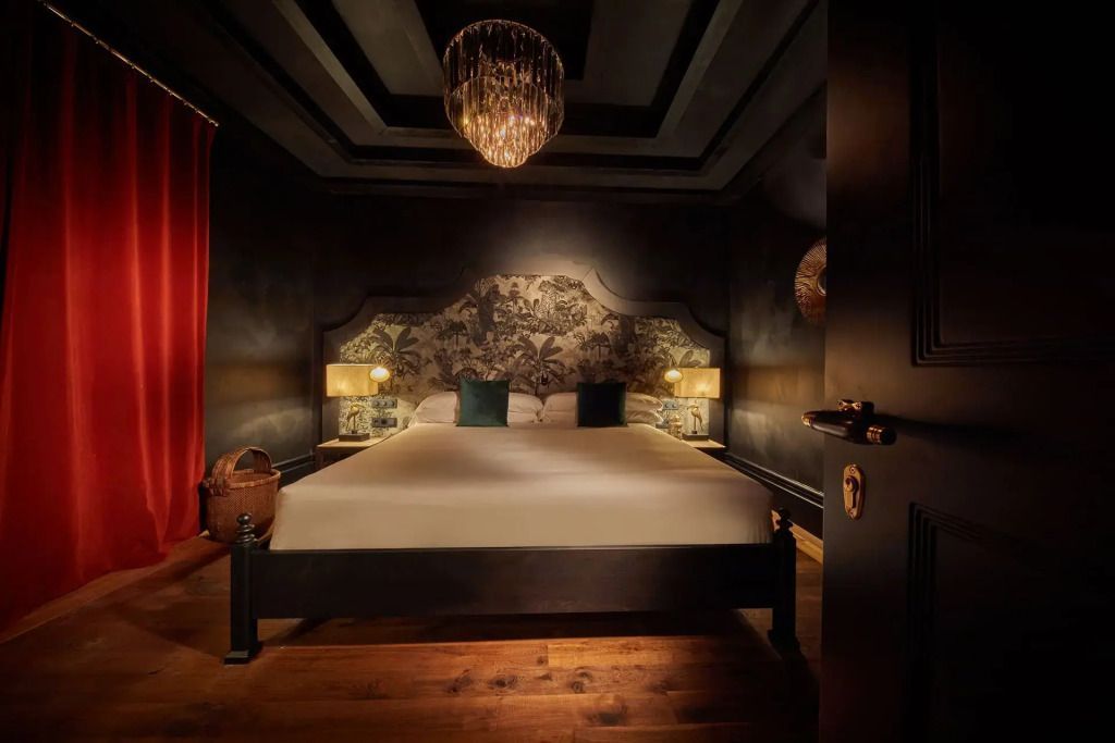 Dunkles Schlafzimmer mit großem Doppelbett und luxuriösem Kronleuchter