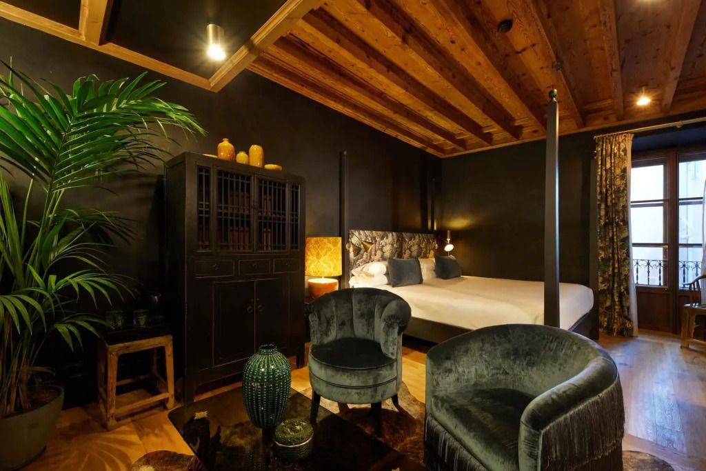 Harmonische Suite mit Doppelbett, Sessel, dunklen Holzmöbeln und dekorativer Beleuchtung
