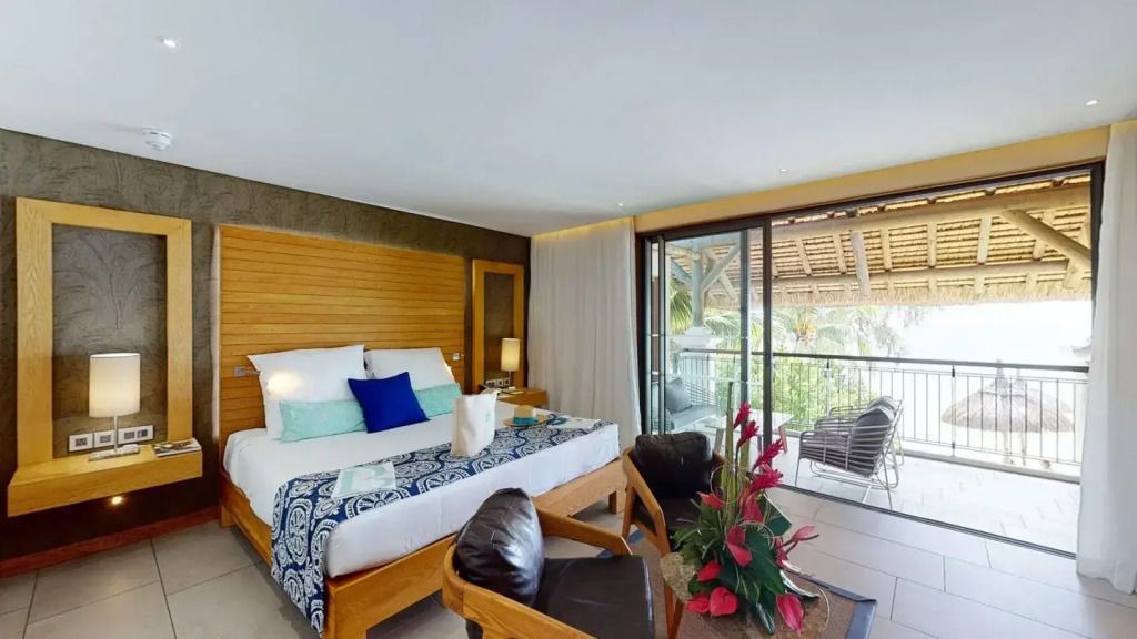 Zimmer mit Blick auf Balkon mit Holzmöbeln und Meerblick im Hintergrund