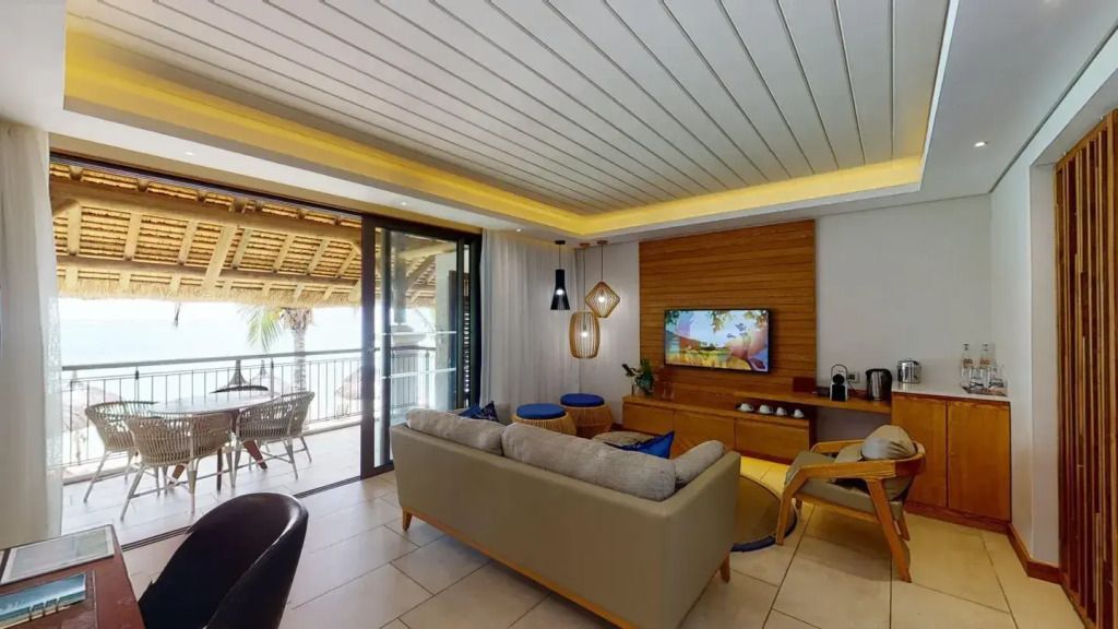 Wohnbereich mit Sofa, Fernseher und Zugang zu Balkon mit Meeresblick