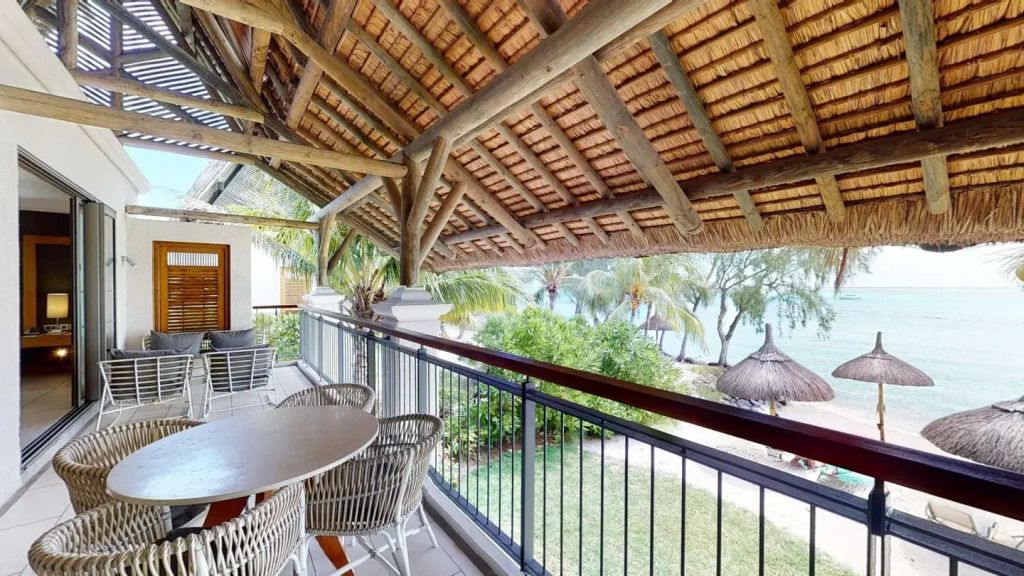 Balkon mit Strohdach, Sitzgelegenheiten und Blick auf tropische Gärten