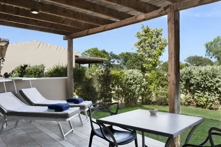 Überdachte Terrasse mit Liegestühlen und Essbereich im Garten.