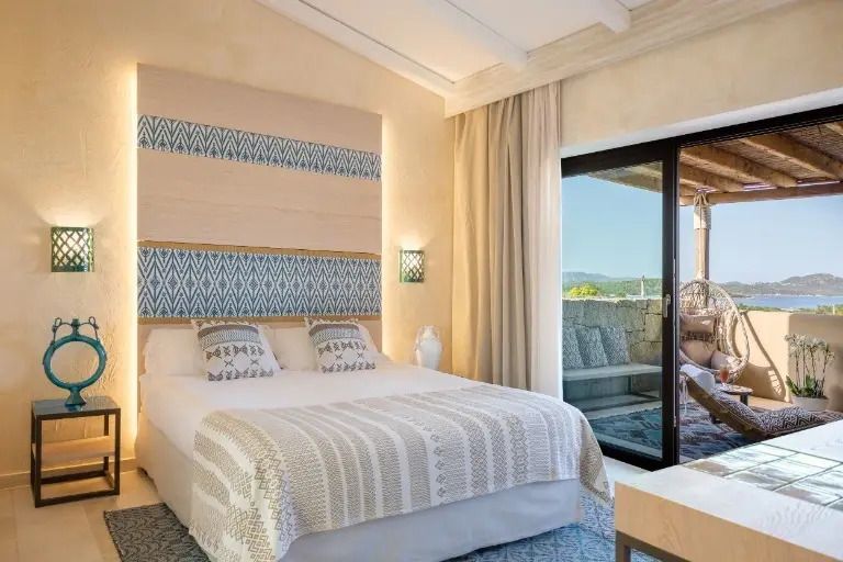 Helles Schlafzimmer in der Maddalena Suite mit Doppelbett und Blick auf die Terrasse