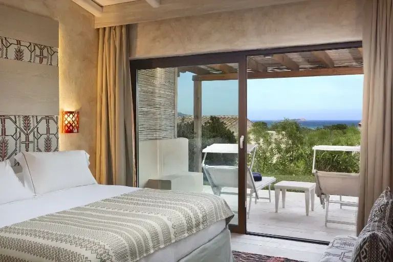Helles Schlafzimmer mit modernem Bett und großem Fenster mit Blick auf die Terrasse und Natur.