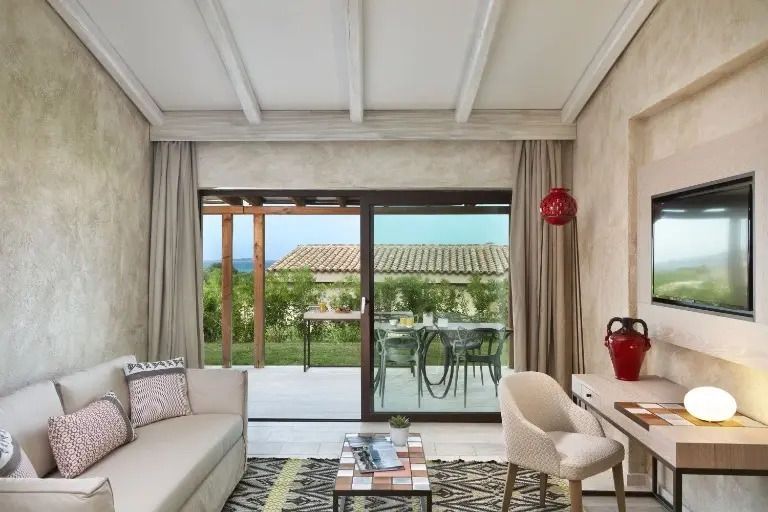 Wohnbereich mit Sofa und Zugang zur Terrasse mit Blick auf mediterrane Landschaft.