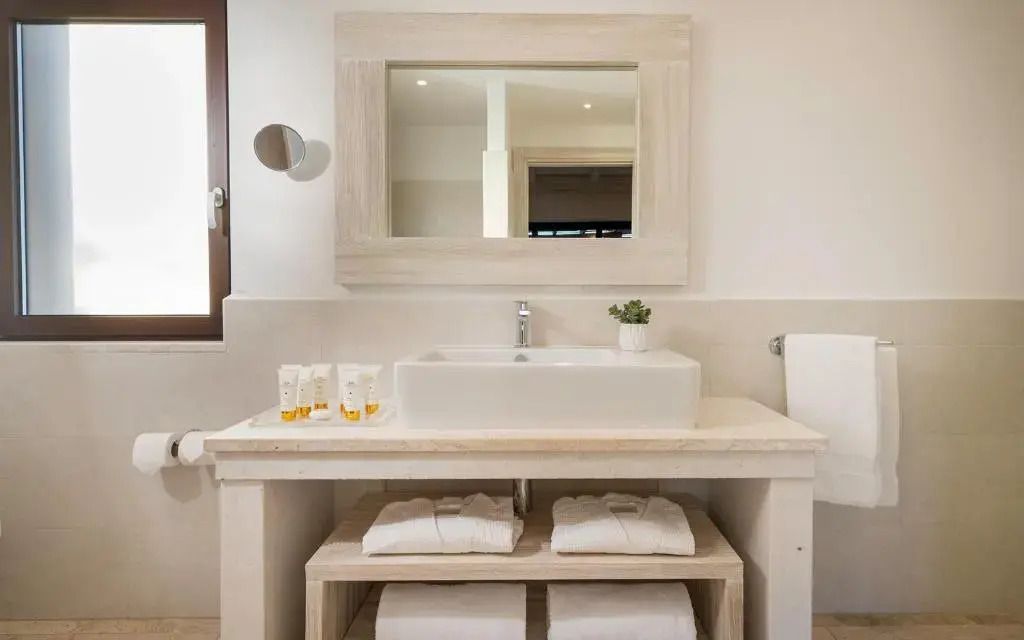 Modernes Badezimmer in der Suite mit Gartenblick im Baglioni Resort Sardinia mit Waschbecken und Spiegel.