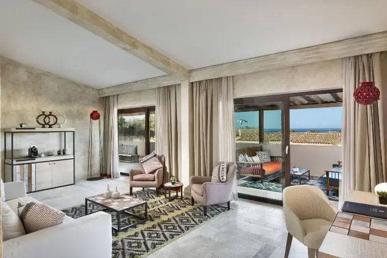 Helles Wohnzimmer einer Suite mit großen Fenstern und Blick auf das Meer