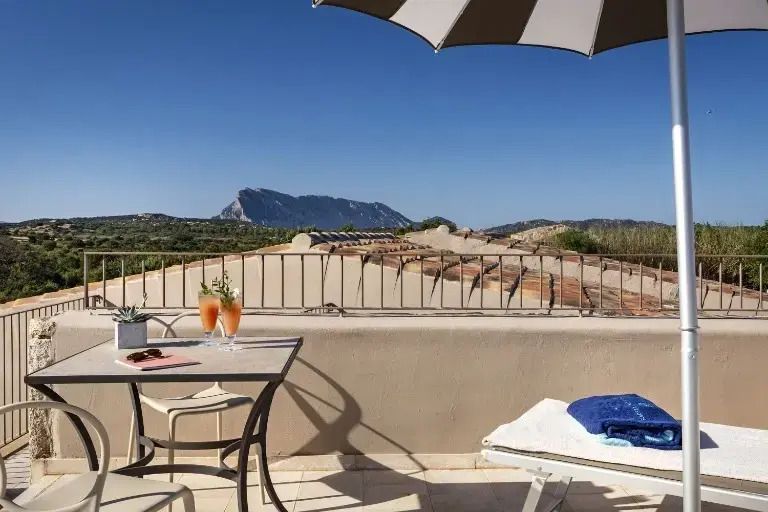 Terrasse mit Bergblick und Cocktailtisch unter blauem Himmel