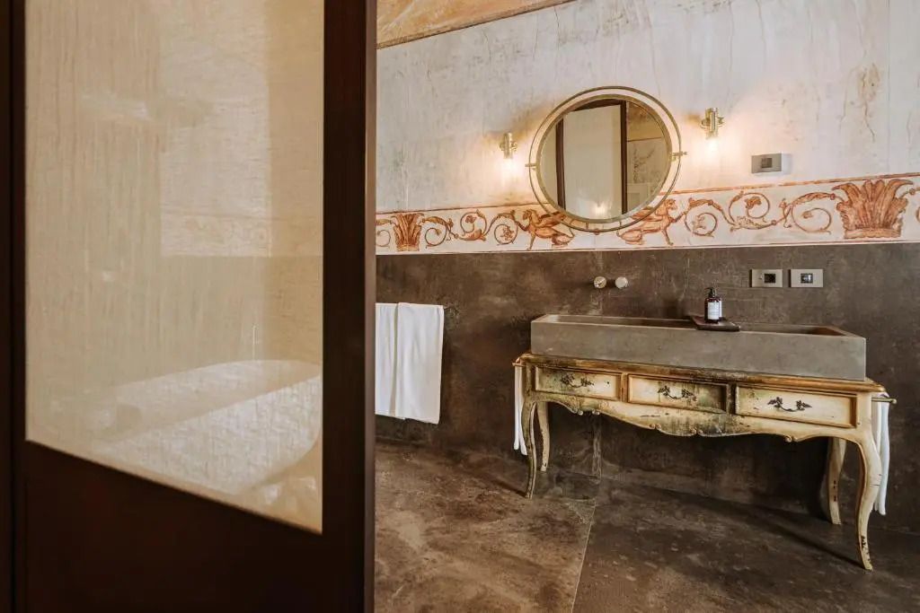 Luxuriöses Badezimmer mit antikem Waschbecken und runden Spiegeln