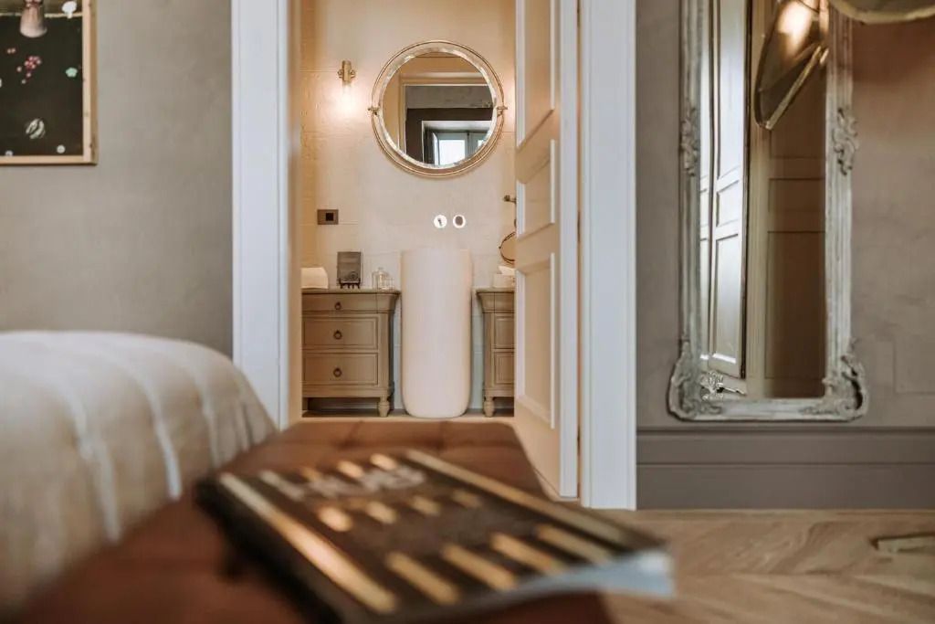 Luxuriöser Badezimmerblick vom Schlafzimmer mit Rundspiegel und eleganter Einrichtung