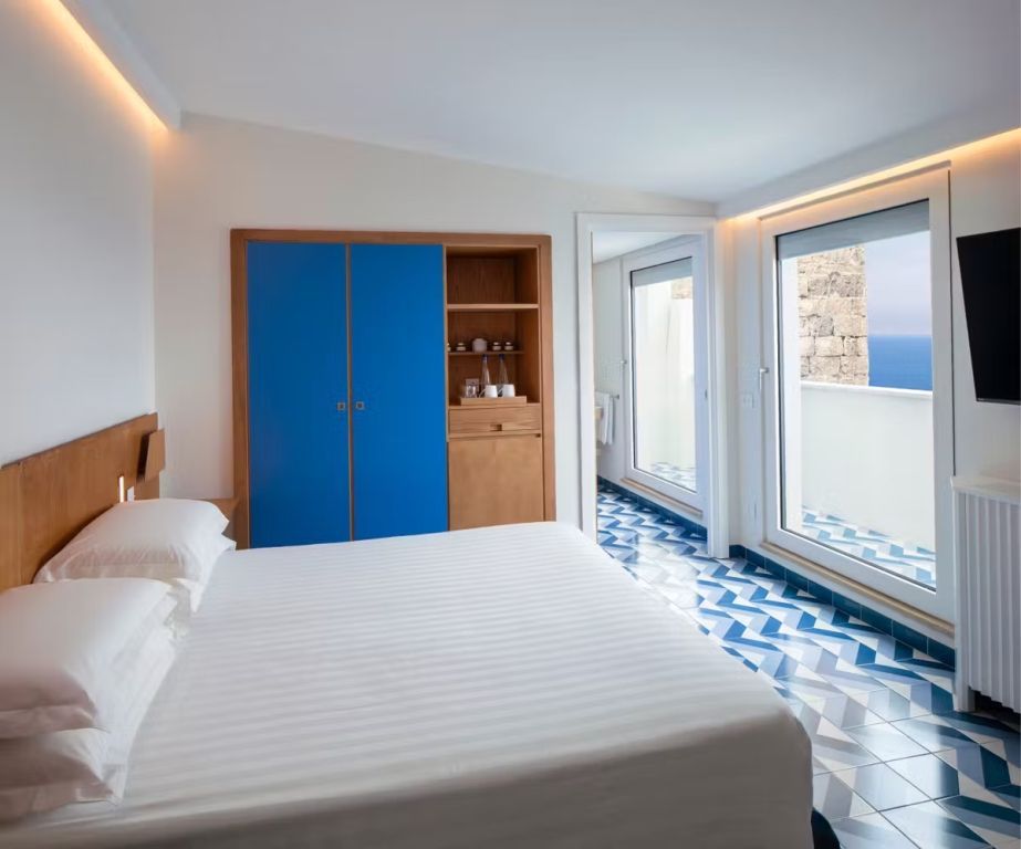 Zimmer mit Doppelbett und großem Fenster zum Meer