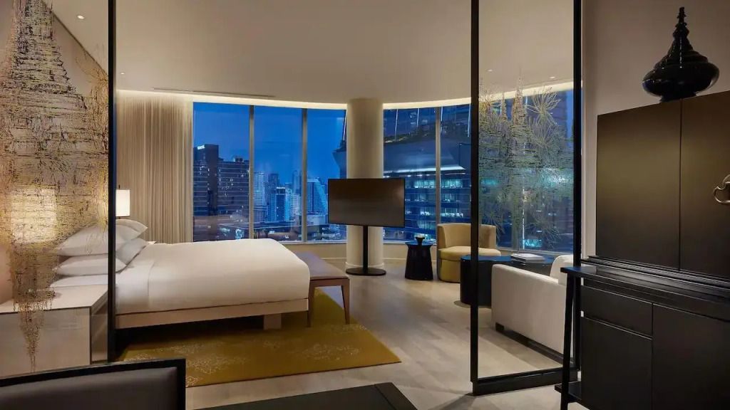 Eckzimmer mit Doppelbett, nächtlicher Stadtblick durch große Fenster