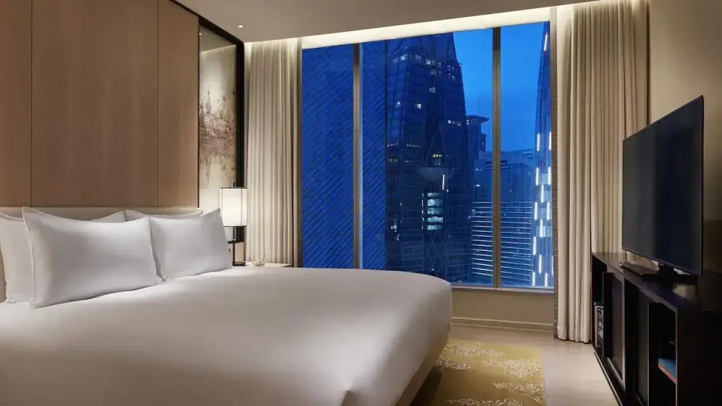 Suite-Schlafzimmer mit großem Fenster und nächtlichem Stadtpanorama