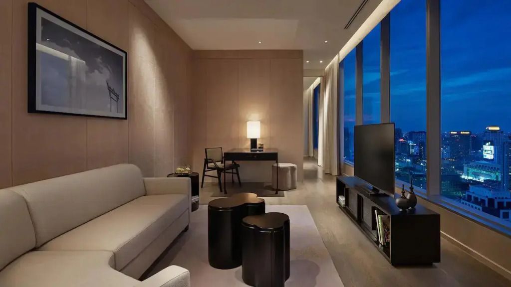 Moderne Suite mit Sofa, Schreibtisch und großem Fenster mit Blick auf die Stadt