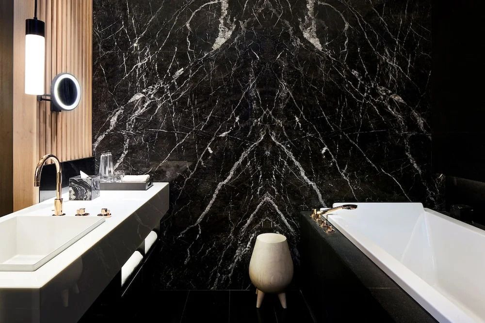 Luxuriöses Badezimmer mit schwarzer Marmordekorwand und moderner Ausstattung