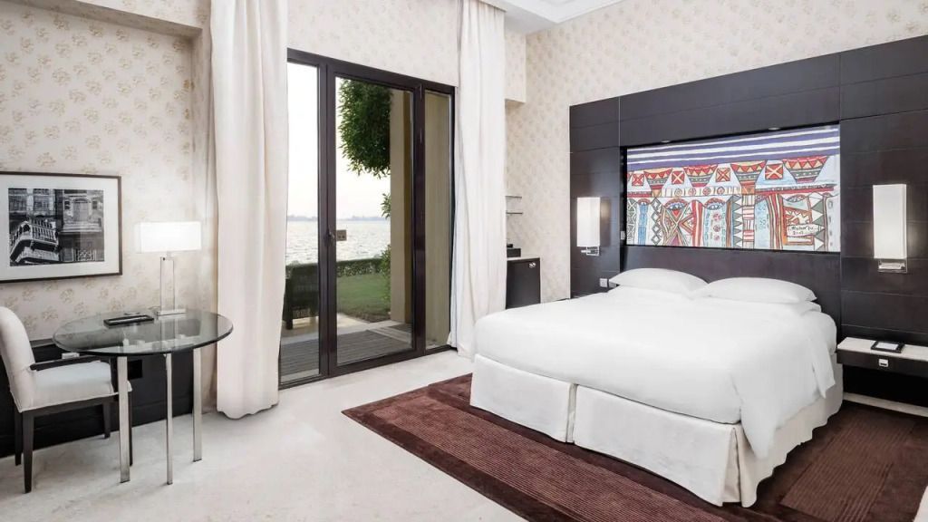 Elegantes Schlafzimmer mit großen Fenstern und Blick auf eine Terrasse am Wasser