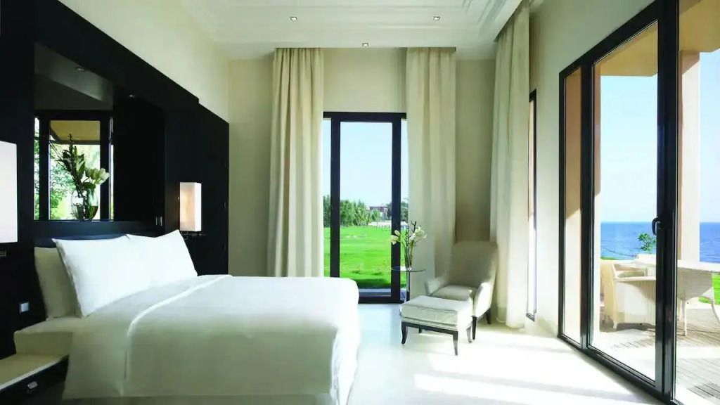 Schlafzimmer mit minimalistischer Einrichtung und grünem Blick durch große Fenster