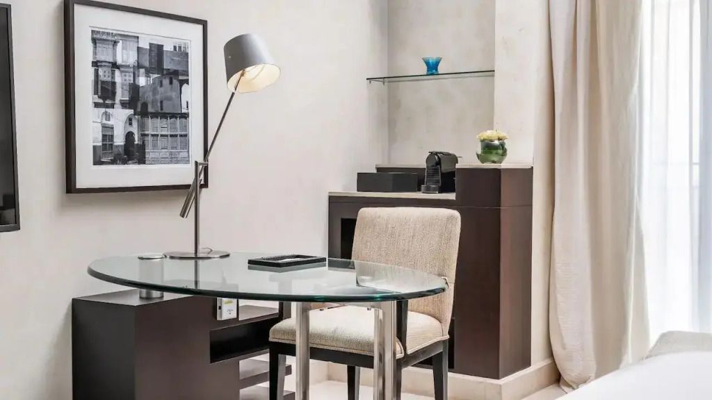 Arbeitsbereich mit Glas-Schreibtisch und moderner Lampe