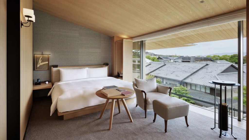 Gemütliches Schlafzimmer mit großem Fenster und Ausblick auf Dächer