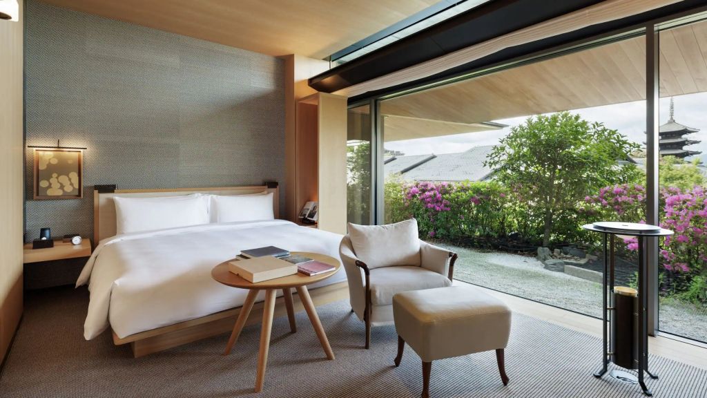 Schlafzimmer mit Bett und Glasschiebetür mit Gartenblick